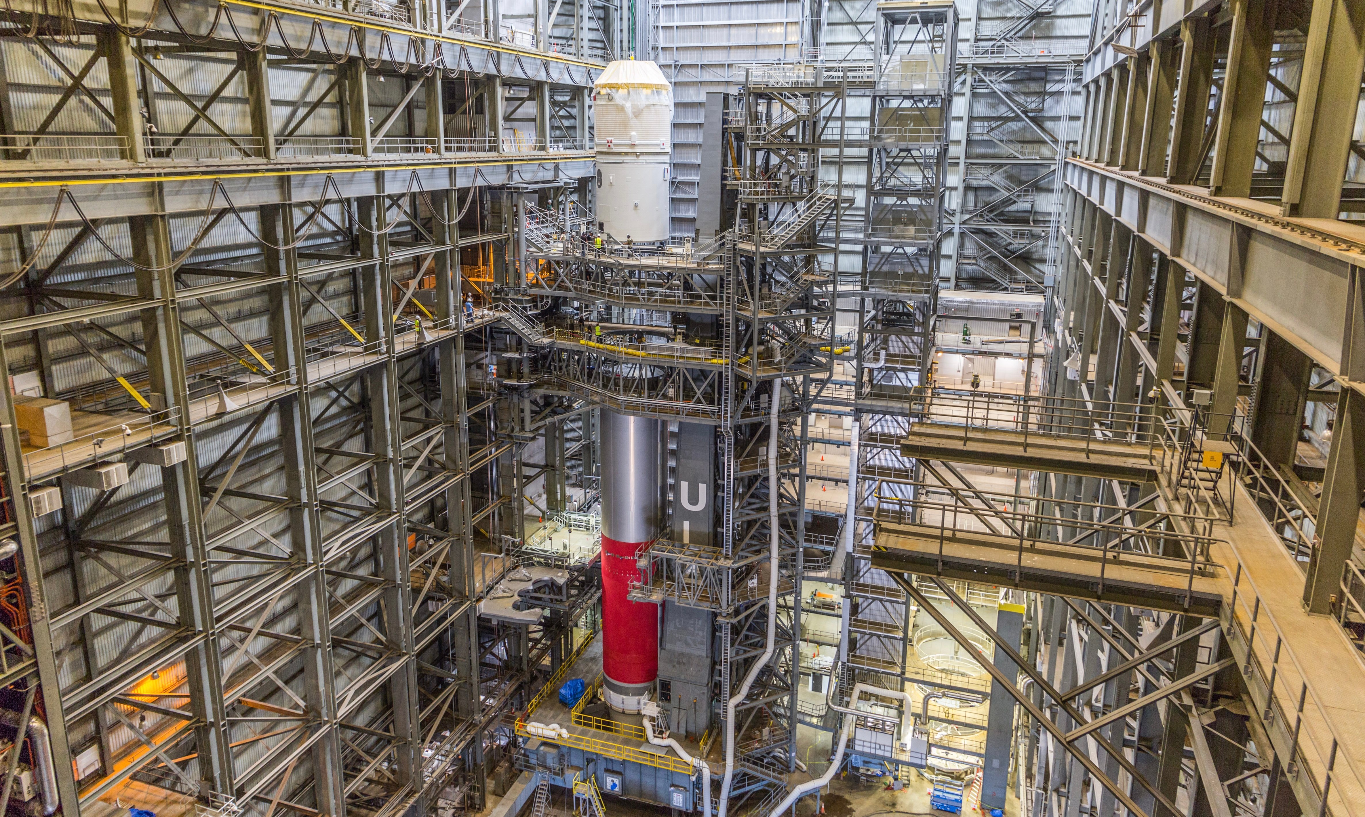 A white Centaur upper stage is lowered onto a red-and-gray Vulcan booster inside ULA’s Amazon integration building.