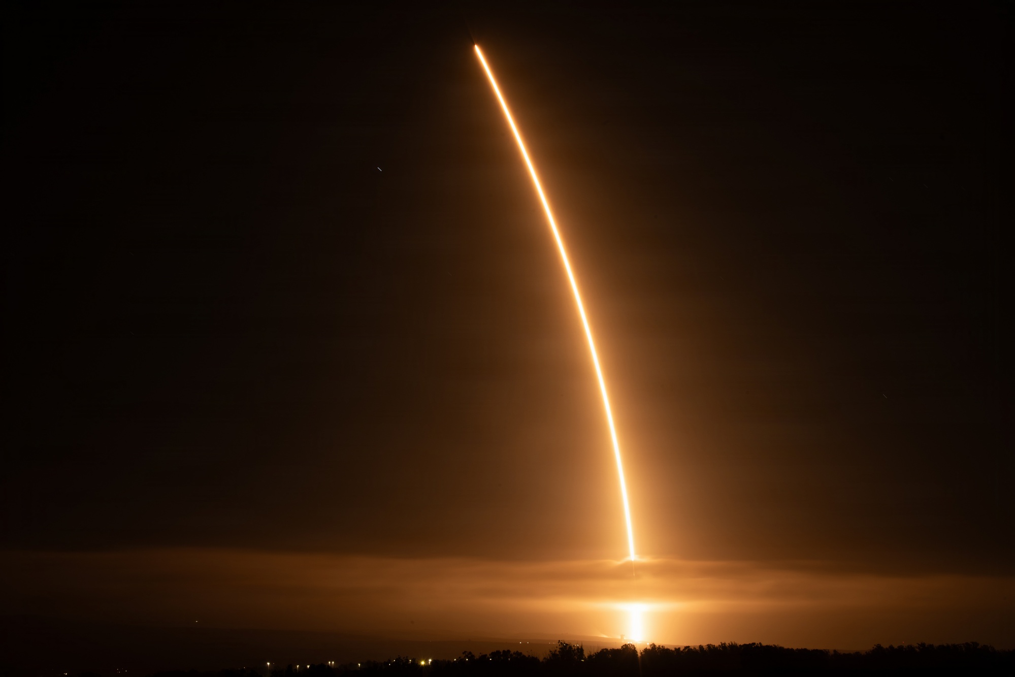 A long exposure traces Falcon 9’s bright ascent above the Pacific coast at night.