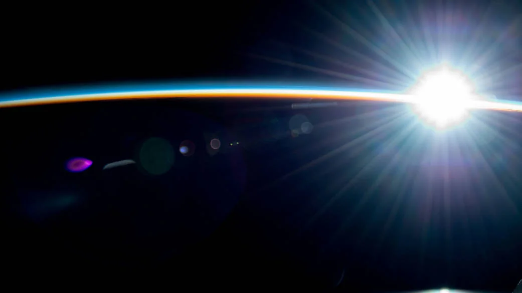 Sunrise over the glowing curve of Earth, photographed from the International Space Station