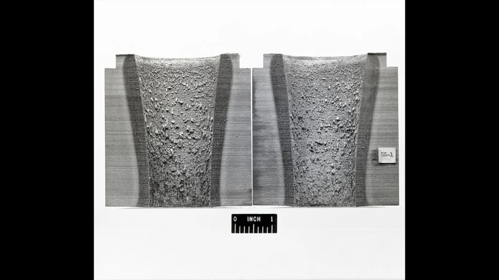 Two cut sections of a rocket nozzle expose textured ablative lining above the supporting structure