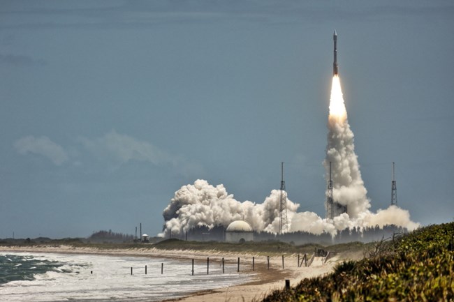 An Atlas V launch viewed across the dunes from a Playalinda Beach boardwalk
